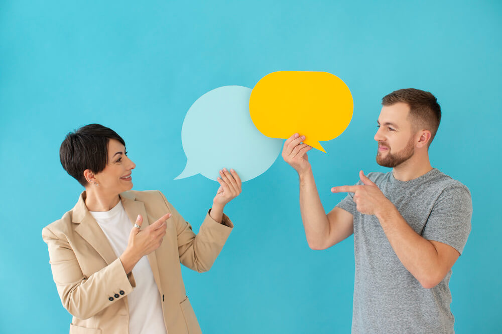 Deux personnes tenant des bulles de dialogue colorées, illustrant un échange dynamique lors d'une permanence de l'association.